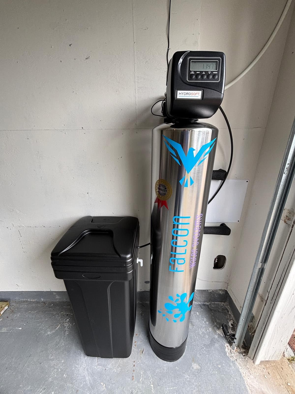 Stainless steel water softener tank with digital metered valve installed in a Houston garage