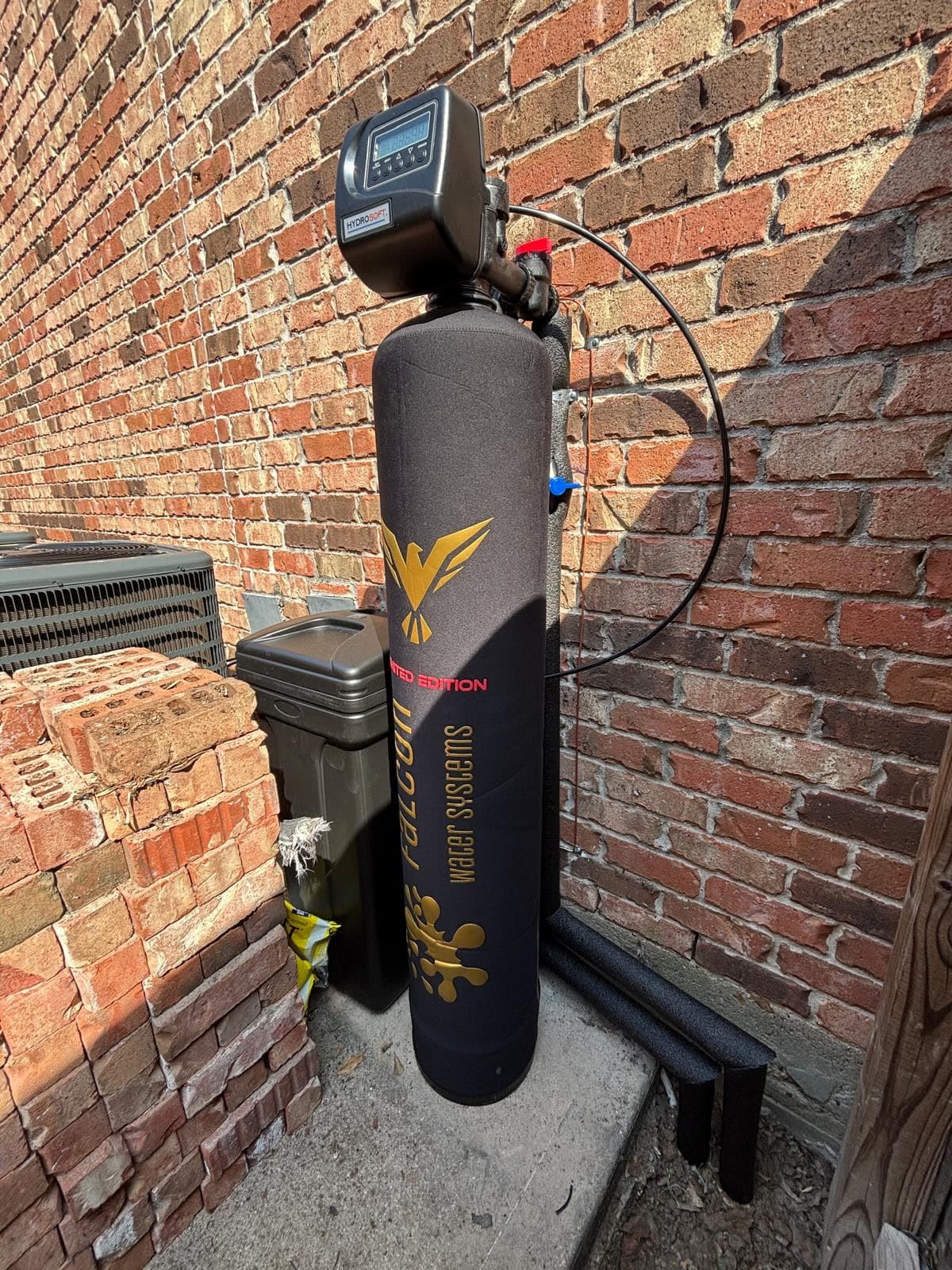 Black and gold Limited Edition tank installed against a brick exterior wall