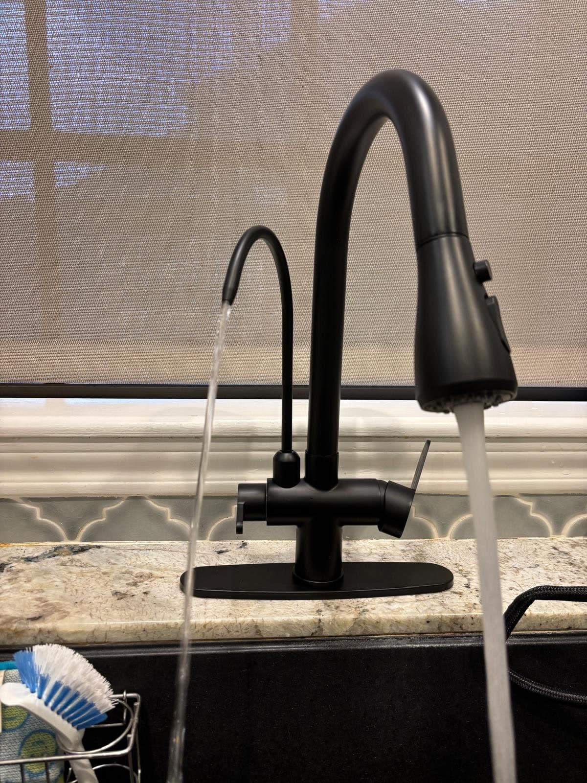 Matte black double reverse osmosis faucet running clean filtered water at the kitchen sink